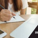 שולחן, ידיים ומחברת. כיתוב: יישומים בשומת מקרקעין